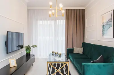 a living room with a green couch and a tv at Bed&Bath Luxury Apartments in Kraków