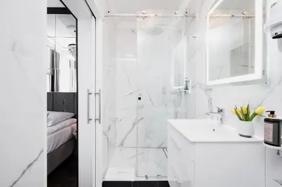 a white bathroom with a shower and a sink at Salomea Krakow apartments in Kraków