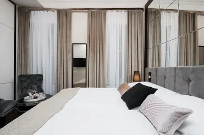 a bedroom with a large white bed and a chair at Salomea Krakow apartments in Kraków