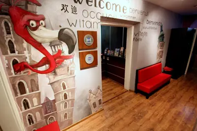 a room with a wall with a painting of a red chair at Flamingo Premium Hostel in Kraków