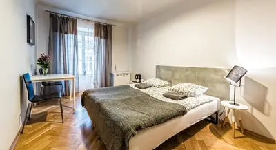 a bedroom with a bed and a desk and a table at Flamingo Premium Hostel in Kraków
