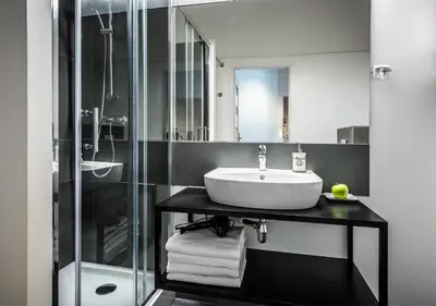 a bathroom with a sink and a glass shower at Flamingo Premium Hostel in Kraków