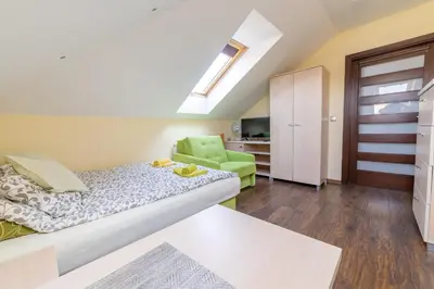 a bedroom with a bed and a green chair at Pokoje Goscinne u Florka in Słopnice