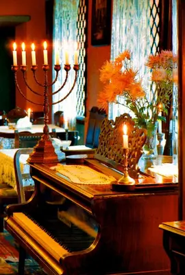 a room with a table with a piano and candles at Austeria Klezmer Hois in Kraków