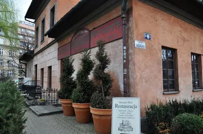 a sign in front of a building with potted plants at Austeria Klezmer Hois in Kraków