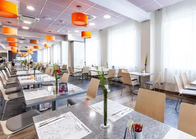 a dining room with tables and chairs and orange lights at Galaxy Hotel in Kraków
