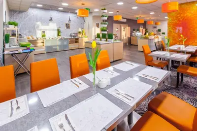 a dining room with a table and orange chairs at Galaxy Hotel in Kraków