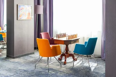 a room with colorful chairs and a chessboard on a table at Galaxy Hotel in Kraków