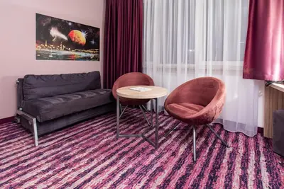 a living room with two chairs and a couch at Galaxy Hotel in Kraków