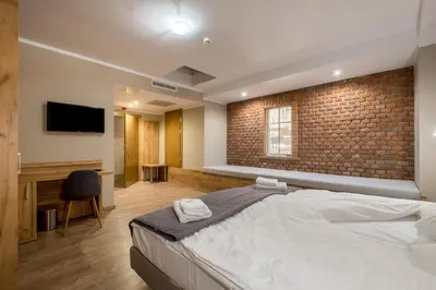 a bedroom with a large bed and a brick wall at Hotel Vinnica in Wieliczka