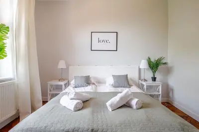 a white bedroom with a large white bed with pillows at Florianska Gate Luxury Apartments in Kraków