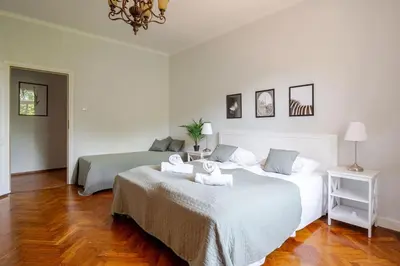 two beds in a room with white walls and wood floors at Florianska Gate Luxury Apartments in Kraków
