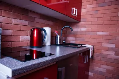 a kitchen with a sink and a red brick wall at Jacuzzi Apartment Red in Kraków