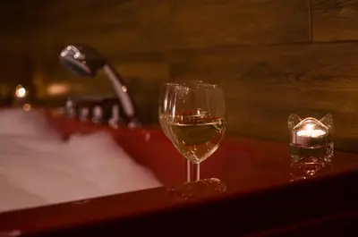 a glass of wine sitting on a table next to a sink at Jacuzzi Apartment Red in Kraków