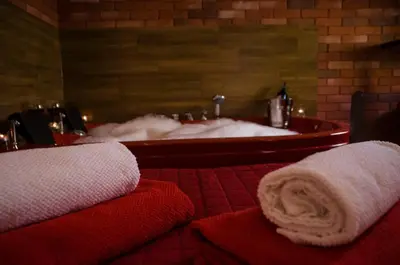a bathroom with a bath tub with towels in front of it at Jacuzzi Apartment Red in Kraków