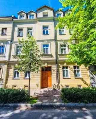 a large building with a brown door and a tree at Jacuzzi Apartment Red in Kraków