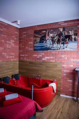 a room with a brick wall and a red tub at Jacuzzi Apartment Red in Kraków