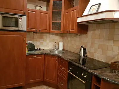 a kitchen with wooden cabinets and a sink at GoldStar Luxury Old Town Krakow Apartment in Kraków