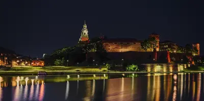 a city at night with a clock tower in the background at GoldStar Luxury Old Town Krakow Apartment in Kraków