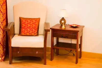 a chair and a nightstand with a lamp and a table at Apartament Kopernik in Kraków