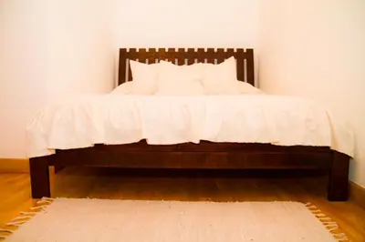 a bed with a white comforter and a rug at Apartament Kopernik in Kraków