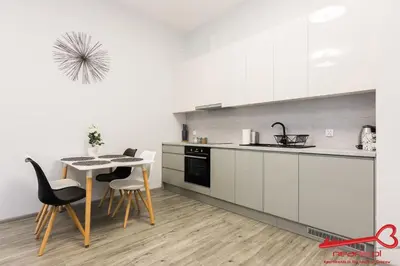 a kitchen with white cabinets and a table and chairs at Apartment Old Town Topolowa in Kraków