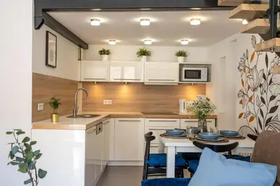 a kitchen with white cabinets and a table with chairs at Home Sweet Home in Kraków