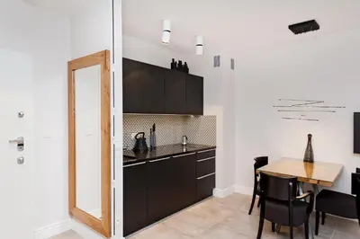 a kitchen with black cabinets and a wooden table at Kazimierz Luxory, Sun & Snow in Kraków