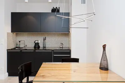 a kitchen with black cabinets and a wooden table at Kazimierz Luxory, Sun & Snow in Kraków