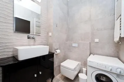 a bathroom with a sink and a washing machine at Kazimierz Luxory, Sun & Snow in Kraków