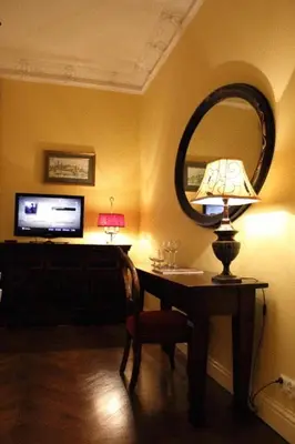 a room with a table with a lamp and a mirror at Cracow Apartments 24 in Kraków