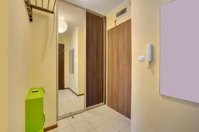 a hallway with a green door and a mirror at Apartament 5 in Kraków