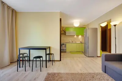 a living room with a table and chairs and a kitchen at Apartament 5 in Kraków