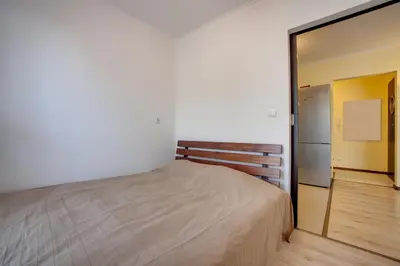 a bedroom with a bed and a door to a kitchen at Apartament 5 in Kraków