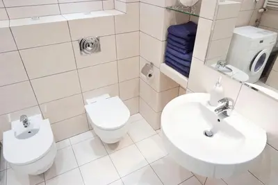 a white bathroom with a toilet and a sink at Trinity Apartment in Kraków