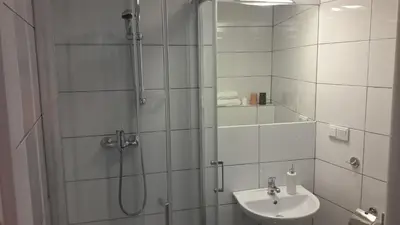 a white bathroom with a shower and a sink at Cracow Central Aparthotel in Kraków