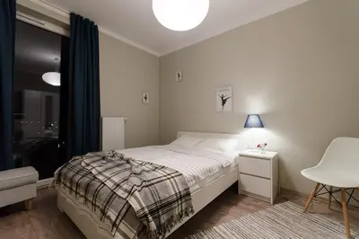 a bedroom with a bed and a table and a chair at White Swan Apartment in Kraków