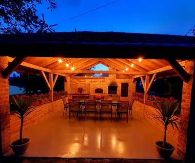 a patio with a table and chairs and lights at Leo House in Gaj