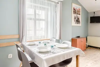 a dining room with a table and chairs and a window at Apartamenty Amber in Kraków