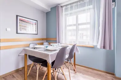 a dining room with a table with chairs and a window at Apartamenty Amber in Kraków