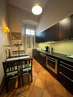 a kitchen with black cabinets and a table and chairs at Main Market Square Apartments in Kraków