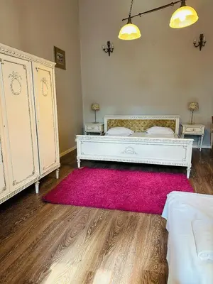a bedroom with a white bed and a pink rug at Main Market Square Apartments in Kraków