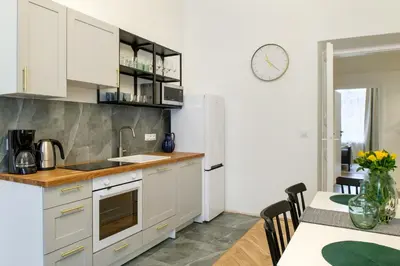 a kitchen with white cabinets and a table with chairs at WAWELOVE spacious 3 bedroom apt 1 min to Main Sq! in Kraków