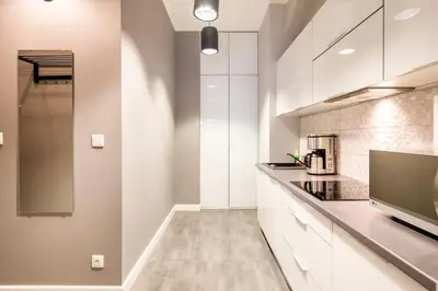 a kitchen with white cabinets and a flat screen tv at Floriańska Glamour Apartments in Kraków