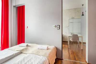 a bedroom with a bed with red curtains and a table at Floriańska Glamour Apartments in Kraków