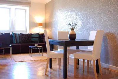a dining room table with white chairs and a vase on it at P&J Apartamenty Grodzka in Kraków