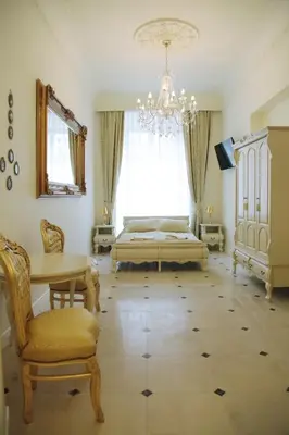 a bedroom with a bed and a table and a chandelier at P&J Apartamenty Grodzka in Kraków