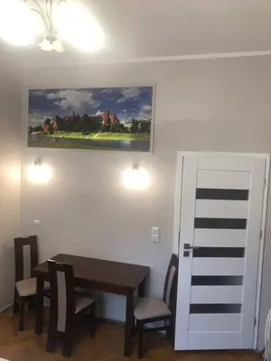 a dining room with a table and chairs and a painting at P&J Apartamenty Św. Krzyża in Kraków