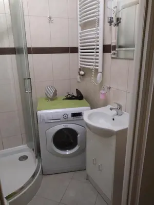 a small bathroom with a washing machine and a sink at AP Na Groblach in Kraków