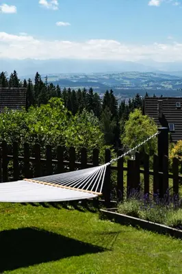 a hammock in a yard with a fence at Apartament Blisko Słońca - Jacuzzi na wyłączność in Nowy Targ